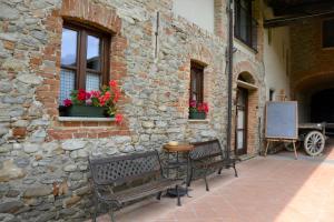 un edificio de piedra con 2 bancos y una mesa con flores en Agriturismo La Pieve, en Dogliani