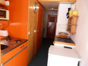 Elle comprend une petite cuisine avec des murs orange et un réfrigérateur blanc. dans l'établissement Résidence Grand Arbois - Studio pour 4 Personnes 73, à Arc 1800