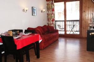 a living room with a red couch and a table at RESIDENCE LA COMBE D OR - 2 Pièces pour 4 Personnes 324 in Les Orres