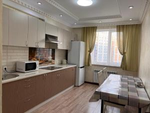 een keuken met een witte koelkast en een tafel bij Apartmens in Complex Almaly 83-51 in Alma-Ata