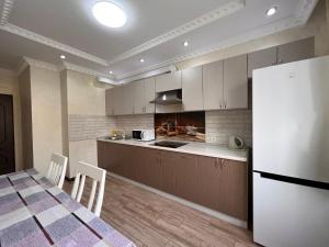 een keuken met een tafel en een witte koelkast bij Apartmens in Complex Almaly 83-51 in Alma-Ata