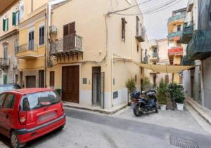 a red car and a motorcycle parked on a street at Appartamenti Franco il Conte in Bagheria