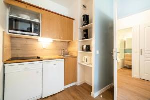 kuchnia z białymi szafkami i mikrofalówką w obiekcie Résidence Les Rives de L'Aure - maeva Home - Appartement 2 pièces 5 personnes - Sélection MAE-6737 w mieście Saint-Lary-Soulan