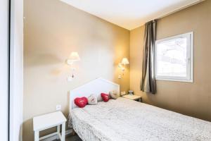 um quarto com uma cama com almofadas vermelhas em Résidence Le Thabor - maeva Home - Appartement 2 Pièces 5 Personnes - Confo 73 em Le Désert