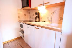 a small kitchen with white cabinets and a sink at Résidence Edelweiss - 3 Pièces pour 8 Personnes 03 in Peisey-Nancroix