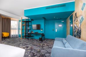a blue living room with a couch and a table at ibis Styles Szczecin Stare Miasto in Szczecin