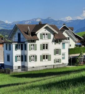 a large white house with mountains in the background at Ferienwohnung Florida in Stein