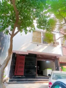 a white building with a red door and a tree at Family Homes in - Dwarka sec 8 Near Yashobhoomi in New Delhi