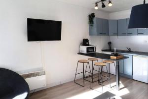 a kitchen with two bar stools and a tv on the wall at Résidence Les Carlines - Studio équipé pour 4 personnes vue pistes MAE-0214 in Les Orres