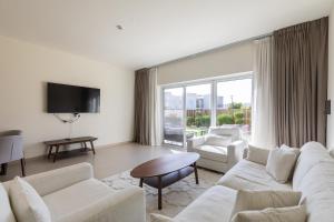 Elle comprend un salon doté d'un mobilier blanc et d'une grande fenêtre. dans l'établissement URBANA III STACKED HOUSE -Dubai South, à Dubaï