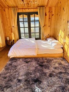 a bed in a wooden room with a large window at Mệ Liệu's House in Da Lat