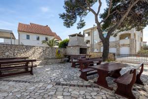 a group of picnic tables and a stone wall at Apartments Eddy Veselica in Novalja