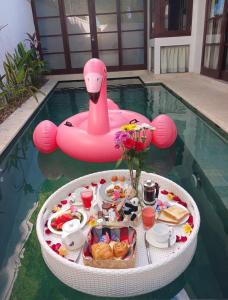 a tray of food in a pool with a pink inflatable at Beautiful Bali Villas in Legian