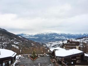 choinkę świąteczną na parkingu z pokrytymi śniegiem górami w obiekcie Résidence Les Carlines - Studio pour 4 Personnes 264 w mieście Les Orres