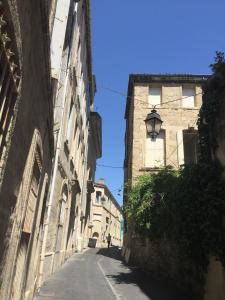 un callejón con dos edificios y un semáforo en "Chambre d'Autres", massages, en Montpellier