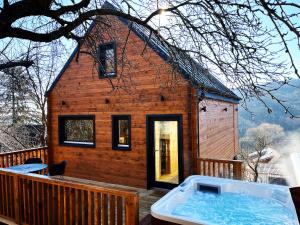 a log cabin with a hot tub on a deck at Woodland Noszvaj in Noszvaj