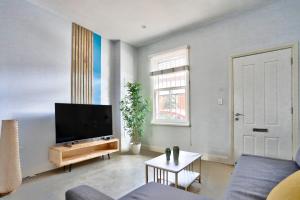 Charming 2 Bedroom House Surry Hills في سيدني: غرفة معيشة مع تلفزيون بشاشة مسطحة وأريكة
