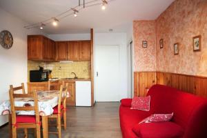 uma sala de estar com um sofá vermelho e uma cozinha em Résidence Les Carlines - Studio pour 4 Personnes 274 em Le Mélézet