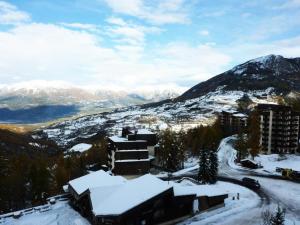 uma montanha coberta de neve com um edifício e uma estrada em Résidence Les Carlines - Studio pour 4 Personnes 274 em Le Mélézet