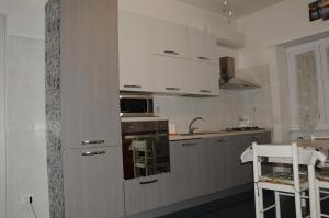 cocina con armarios blancos, fregadero y fogones en Appartamento Palmira, en Roma