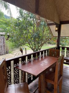 einen Holztisch und Stühle auf einem Balkon mit einem Baum in der Unterkunft Mango House in Ko Lanta