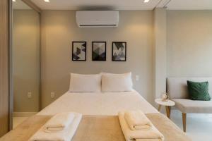 een slaapkamer met een groot wit bed en een stoel bij B Homy Paraíso - Studio espaçoso c design AHZ1004 in Sao Paulo