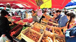 eine Gruppe von Menschen, die um einen Markt mit Kisten Gemüse stehen in der Unterkunft Le Nordmann - au coeur de Gérardmer in Gérardmer