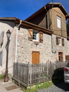 ein Steinhaus mit einem Zaun und einer Straßenbeleuchtung in der Unterkunft Le Nordmann - au coeur de Gérardmer in Gérardmer