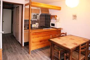 a small kitchen with a table and a microwave at Résidence Le Pouzenc - Studio pour 4 Personnes 824 in Le Mélézet