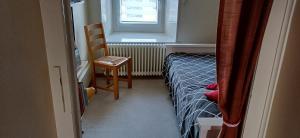 una camera da letto con un letto, una sedia e una finestra di Halte au pied du Creux du Van a Travers