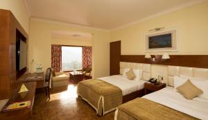 a hotel room with two beds and a television at Gem Park Ooty in Ooty