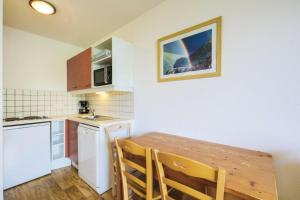a small kitchen with a wooden table and chairs at Résidence Le Hameau des Ecrins - maeva Home - Appartement 2 Pièces 6 Person 50 in Puy-Saint-Vincent