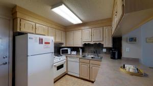 a kitchen with white cabinets and a white refrigerator at Beachmaster Unit 107 in Cherry Grove is an Oceanfront Condo in Myrtle Beach +12 photos
