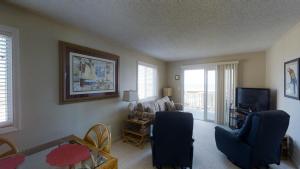 a living room with a couch and a tv and chairs at Beachmaster Unit 107 in Cherry Grove is an Oceanfront Condo in Myrtle Beach