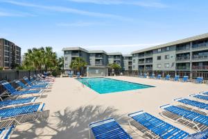 a swimming pool with blue lounge chairs and a building at Sea Cabin Unit 125 Cherry Grove in Myrtle Beach