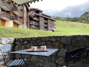 two coffee cups on a table in front of a stone wall at PORTAIL G - Appartement PORTAIL 51 pour 2 Personnes 00 in Valmorel