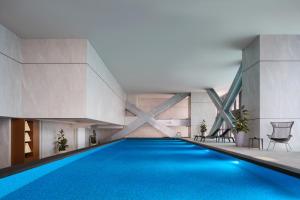 a swimming pool in a building with blue water at PARKROYAL Serviced Suites Jakarta in Jakarta