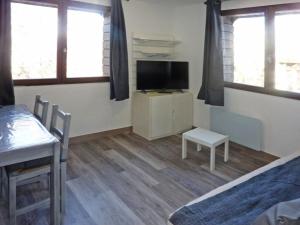 1 dormitorio con mesa, TV, mesa y silla en Résidence Les Flocons - 2 Pièces pour 6 Personnes 654 en Le Mélézet