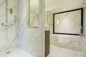 bagno bianco con doccia e lavandino di Hotel Concortel Paris a Parigi