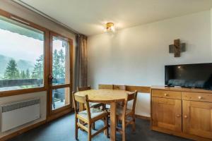 a dining room with a table and a television at CHEVAL BLANC G - Appartement CHEVAL BLANC E08 pour 4 Personnes 31 in Valmorel