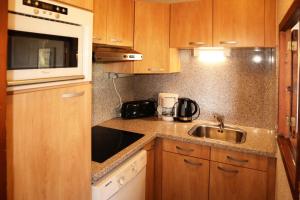 a kitchen with wooden cabinets and a sink and a microwave at Résidence Le Belvedere - APPARTEMENT N° 1104 LE BELVEDERE MAE-3764 in Le Mélézet