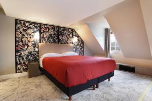 - une chambre mansardée avec un grand lit rouge dans l'établissement Hotel Concortel Paris, à Paris