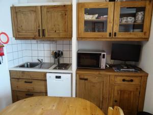 Una cocina con armarios de madera, fregadero y microondas. en Résidence Fond Blanc - Studio pour 3 personnes à Arc 2000 proche des commerces et des pistes MAE-2149, en Arc 2000