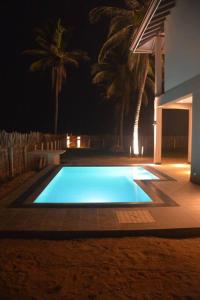 duży niebieski basen w ogrodzie w nocy w obiekcie Nayan's Paradise Beach Villa w mieście Puttalam
