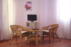 Habitación con mesa, sillas y TV. en Hostal Zaguan, en Talaveruela