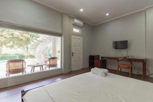 a bedroom with a bed and a balcony with a television at Urbanview Resort Botol Cisarua Puncak Bogor in Tagalbato