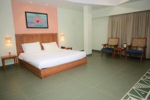 a bedroom with a large bed and two chairs at Hotel Ashray in Ujjain