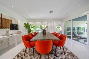 a kitchen with a wooden table and orange chairs at Boho House - Stylist Home with Parking and large Yard in Miami