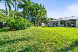 a green yard with palm trees and a building at Boho House - Stylist Home with Parking and large Yard in Miami