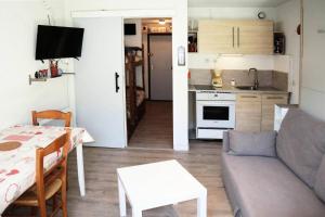 un soggiorno con divano e tavolo e una cucina di Résidence Pic Vert - Studio pour 4 Personnes 204 a Les Orres